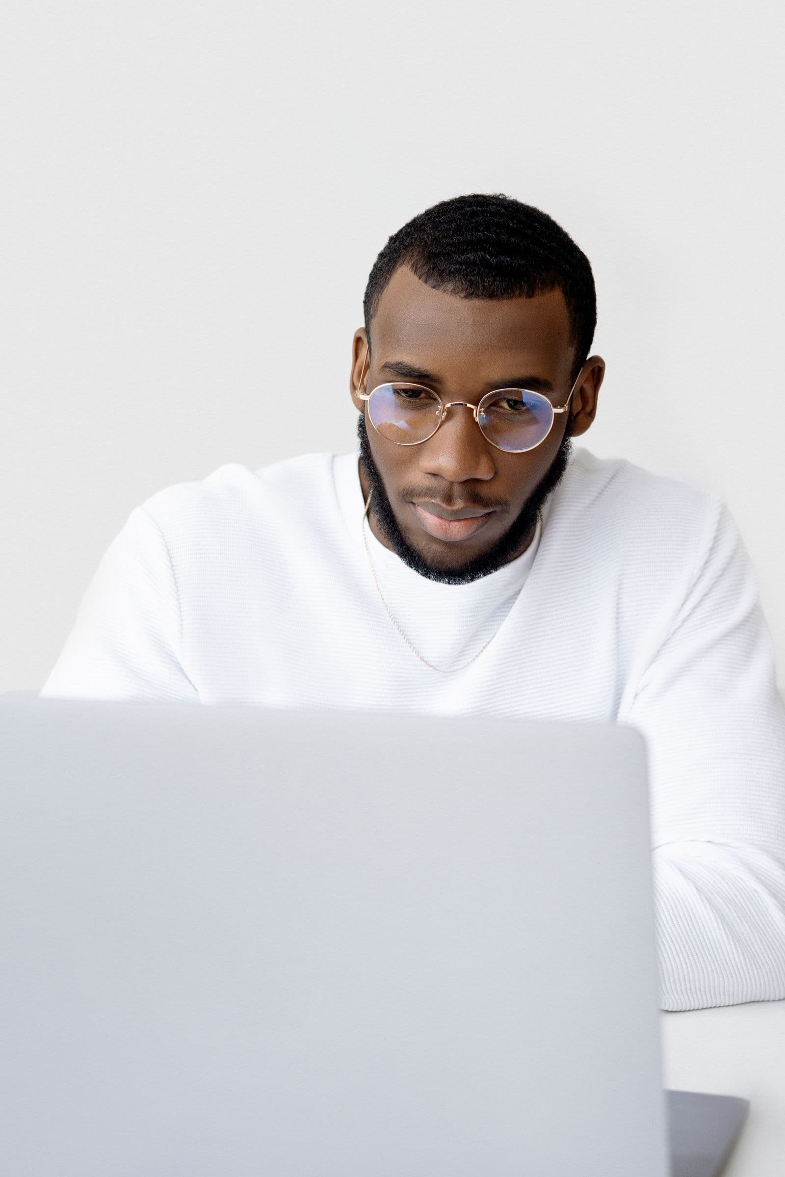 A man wearing glasses working at a laptop