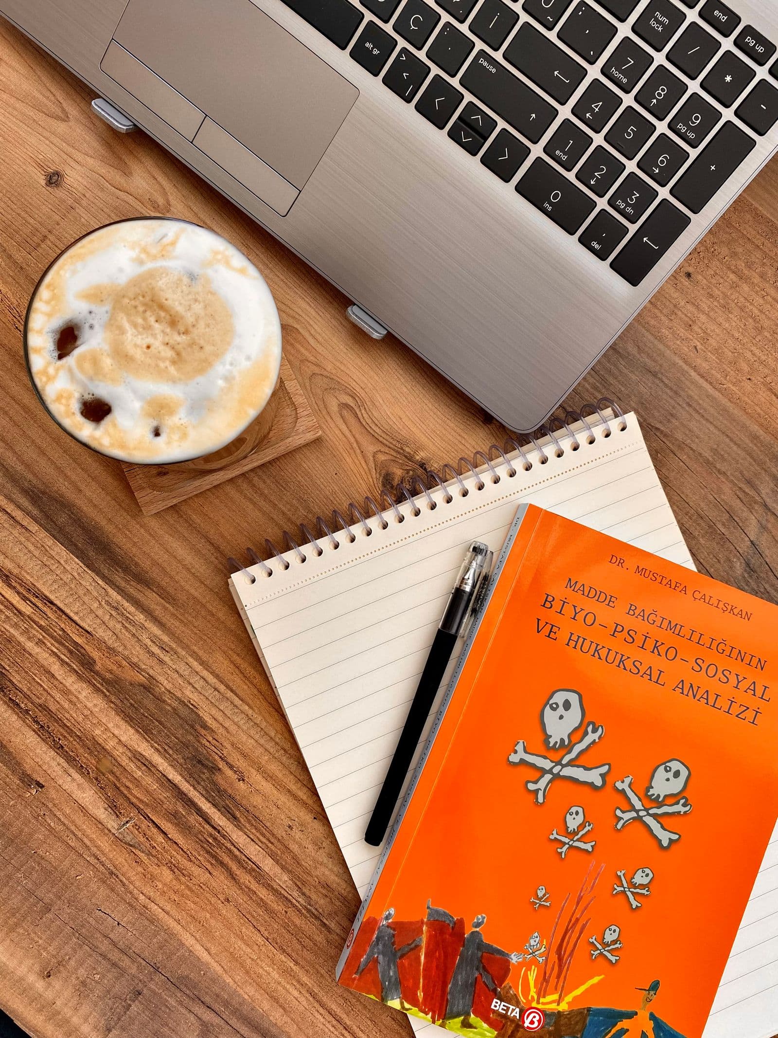 Coffee, books, and a notebook arranged beside a laptop