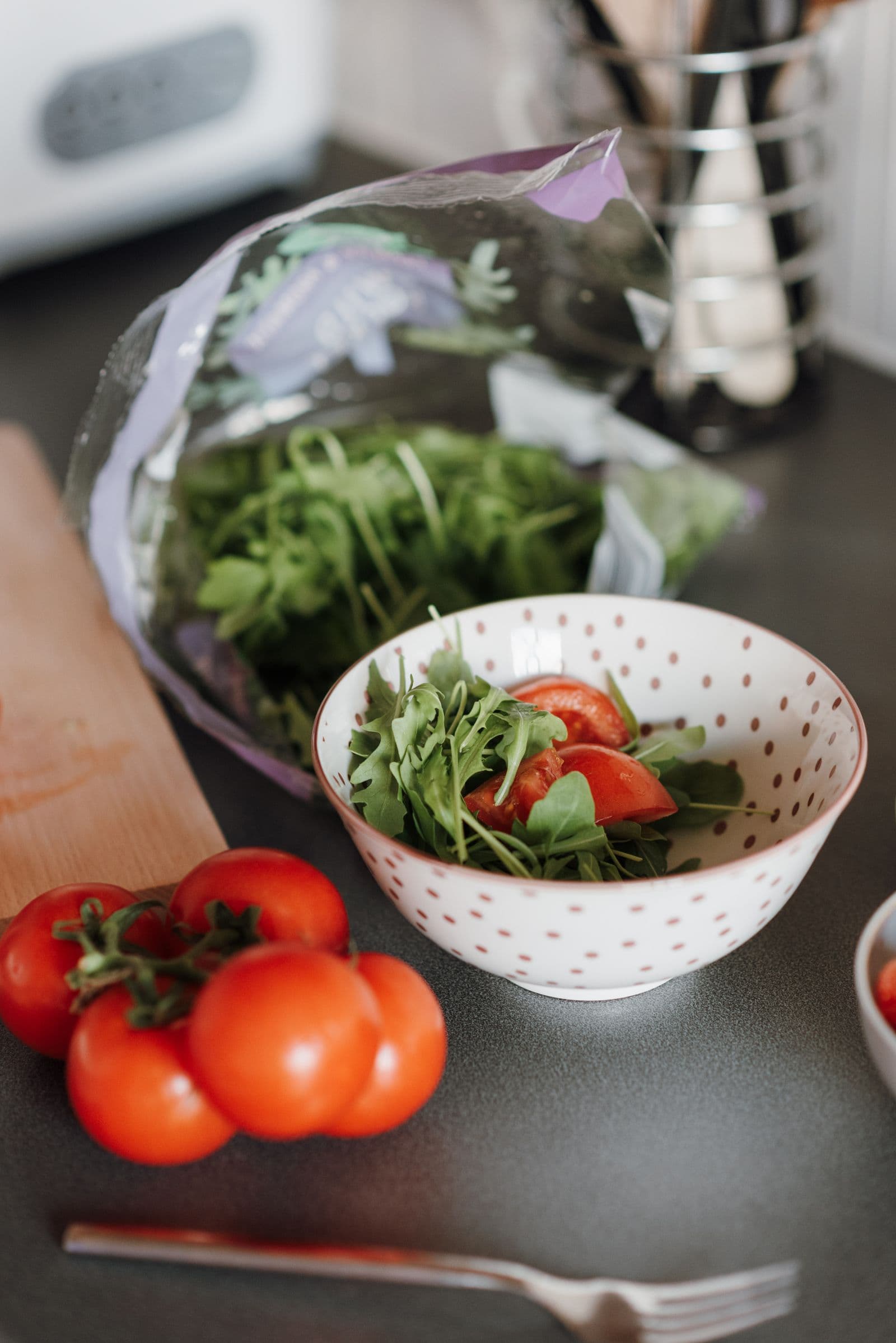 Fresh tomatoes and leafy greens in a bowl